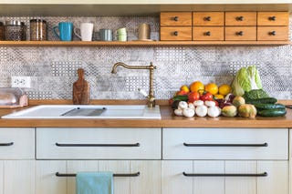 stack of edible mushrooms, vegetables and fruits tomatos, avocado, zucchini, oranges, apples, grapefruits, kohlrabi, chinese cabbage, savoy cabbage, cucumbers, radicchio on countertop in modern rustic kitchen