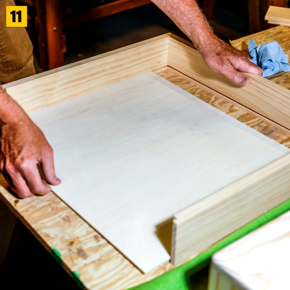 manos ensamblando una caja de madera con un panel interior liso