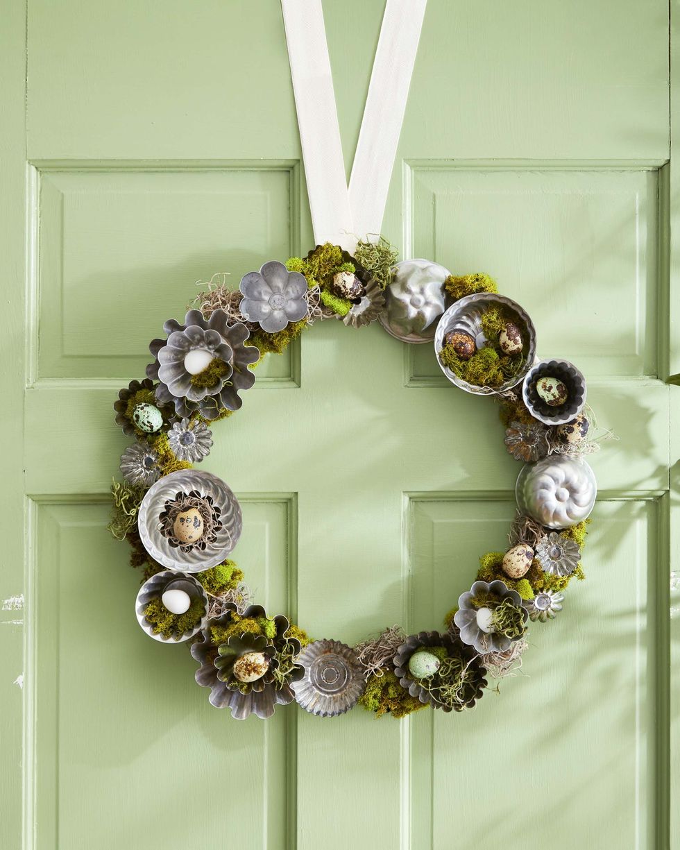 A moss wreath decorated with small baking molds and quail eggs, painted on a pale green door