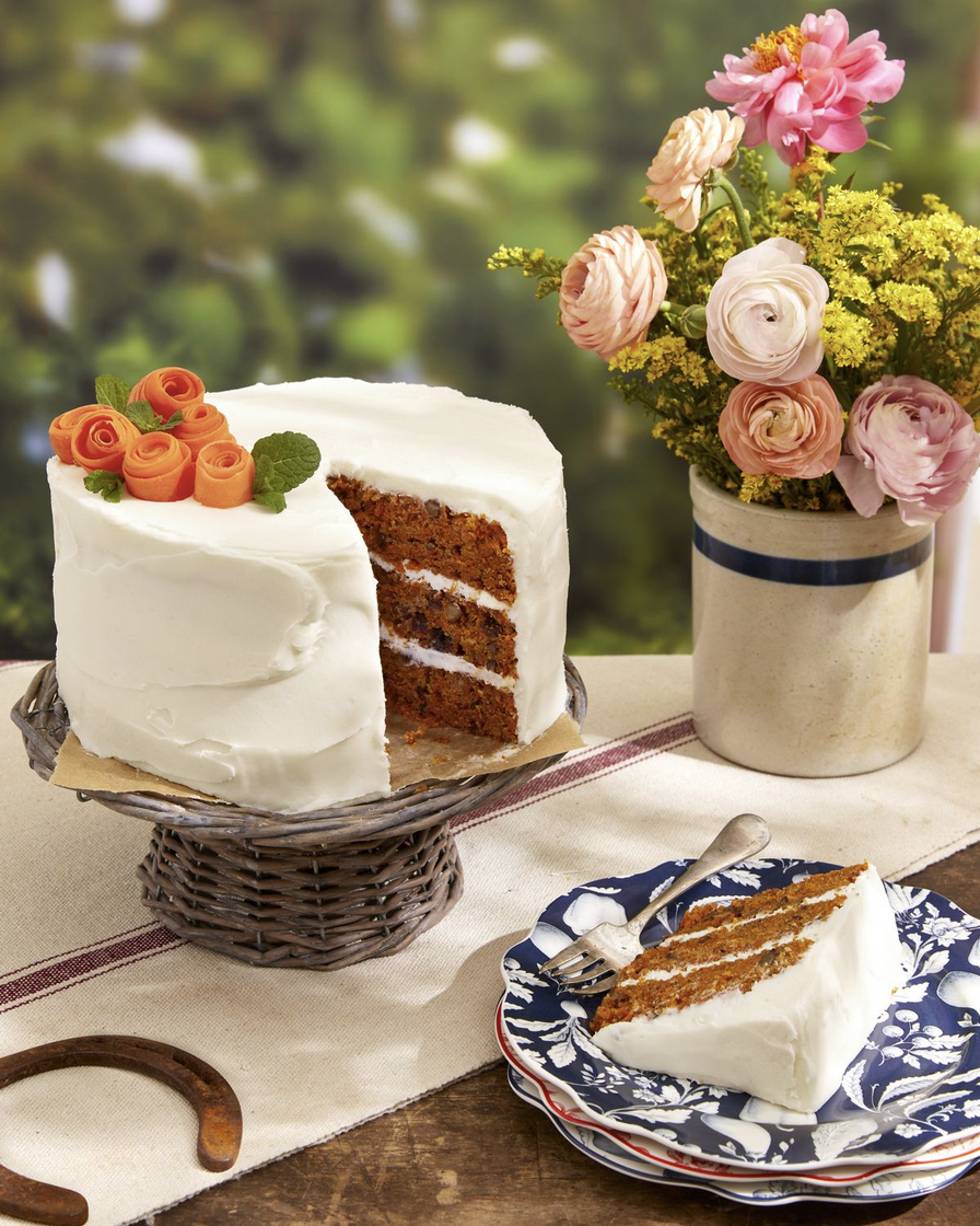 a carrot cake sitting on a cake stand with one slice out on a plate