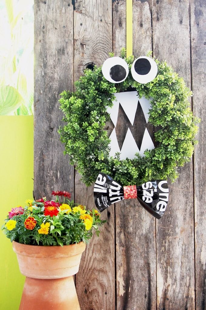 diy outdoor halloween decorations, wreath with a monster face on the fence outdoors