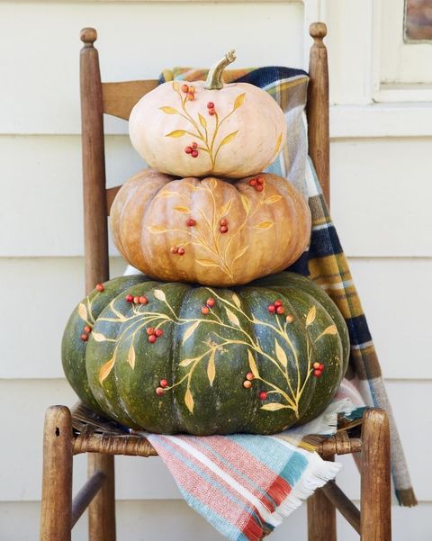 stack of pumpkins etched with a botanical design on a wood chair