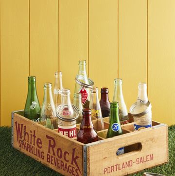 a soda crate filled with soda bottles and mason jar rings around their necks