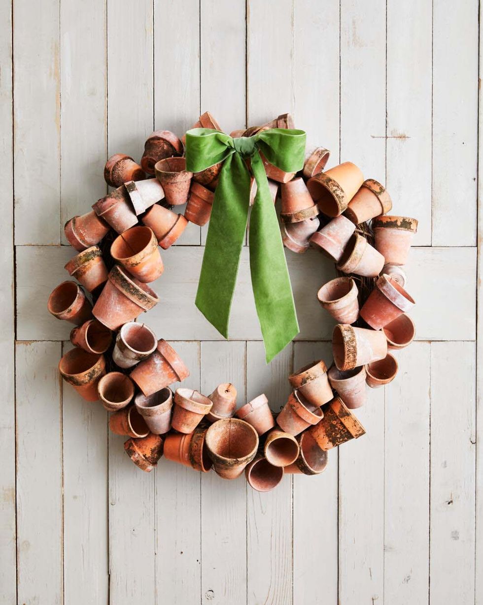 a wreath made from small aged terra cotta pots hung on a white barn door