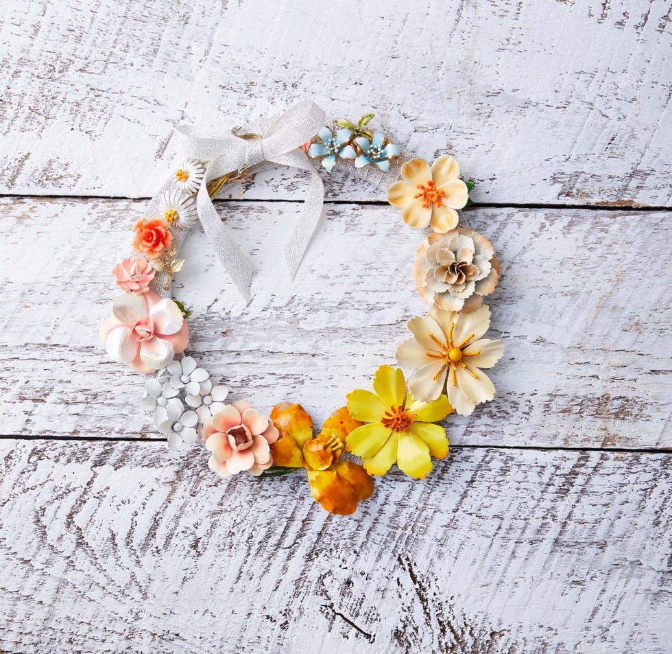 a wreath made from colorful flower shaped brooches hung on a white background