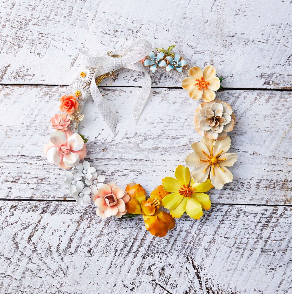 a wreath made from colorful flower shaped brooches hung on a white background