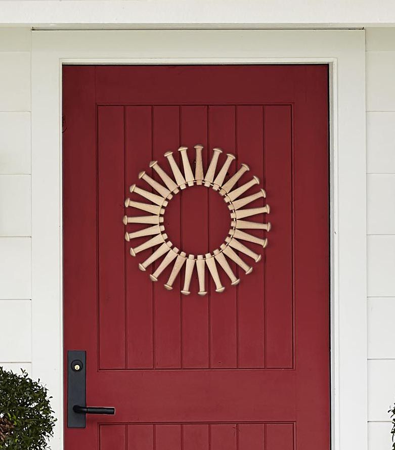 a wreath made from shaker pegs hung on a red door