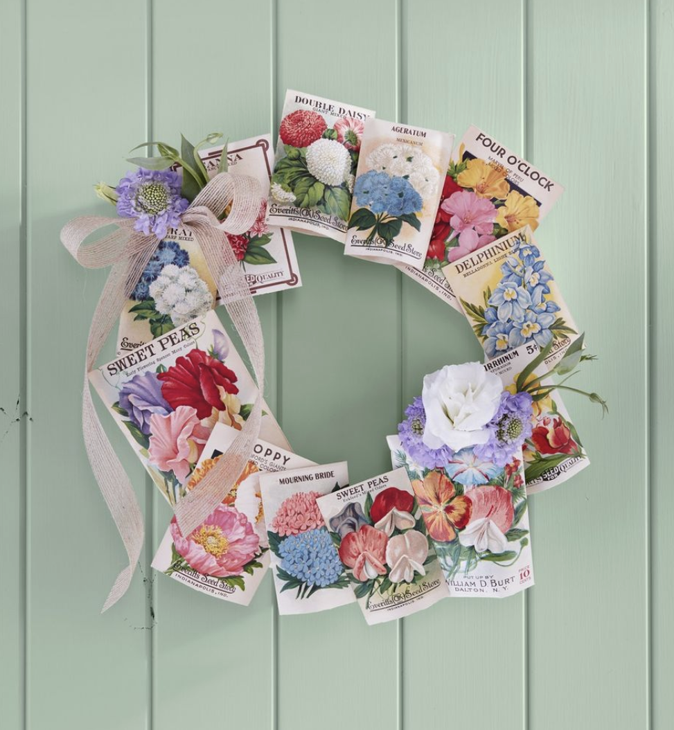 a wreath made from vintage seed packets hung on a light green background