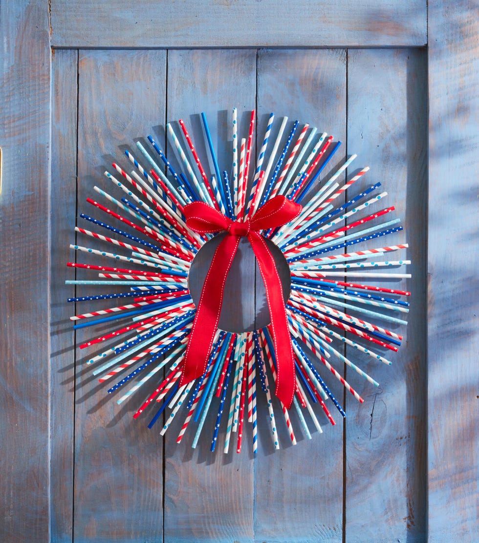 Starburst style wreath made of red, white and blue flags hung on a blue door