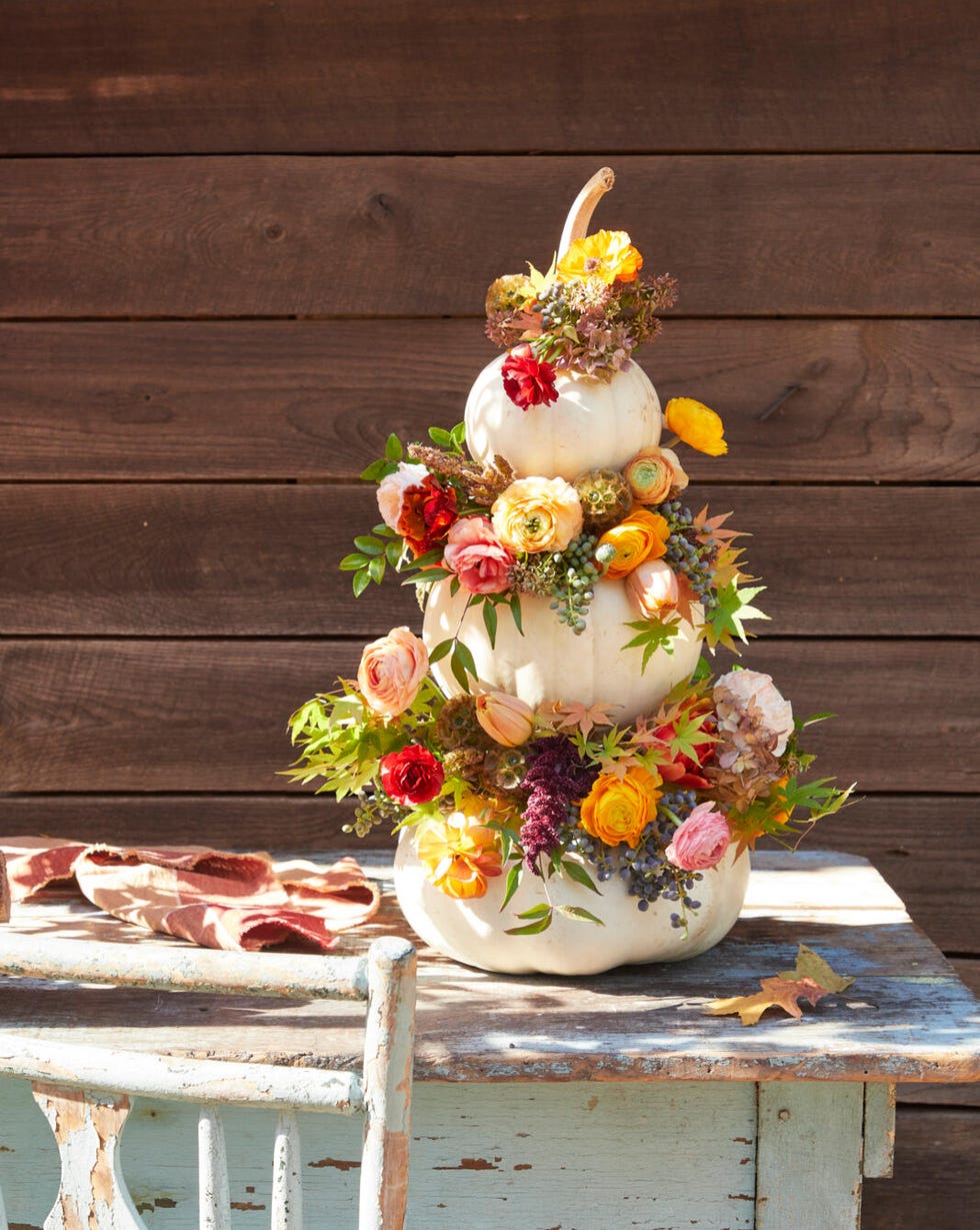 three stacked white pumpkins with fall flowers tucked into the space where the pumpkins meet