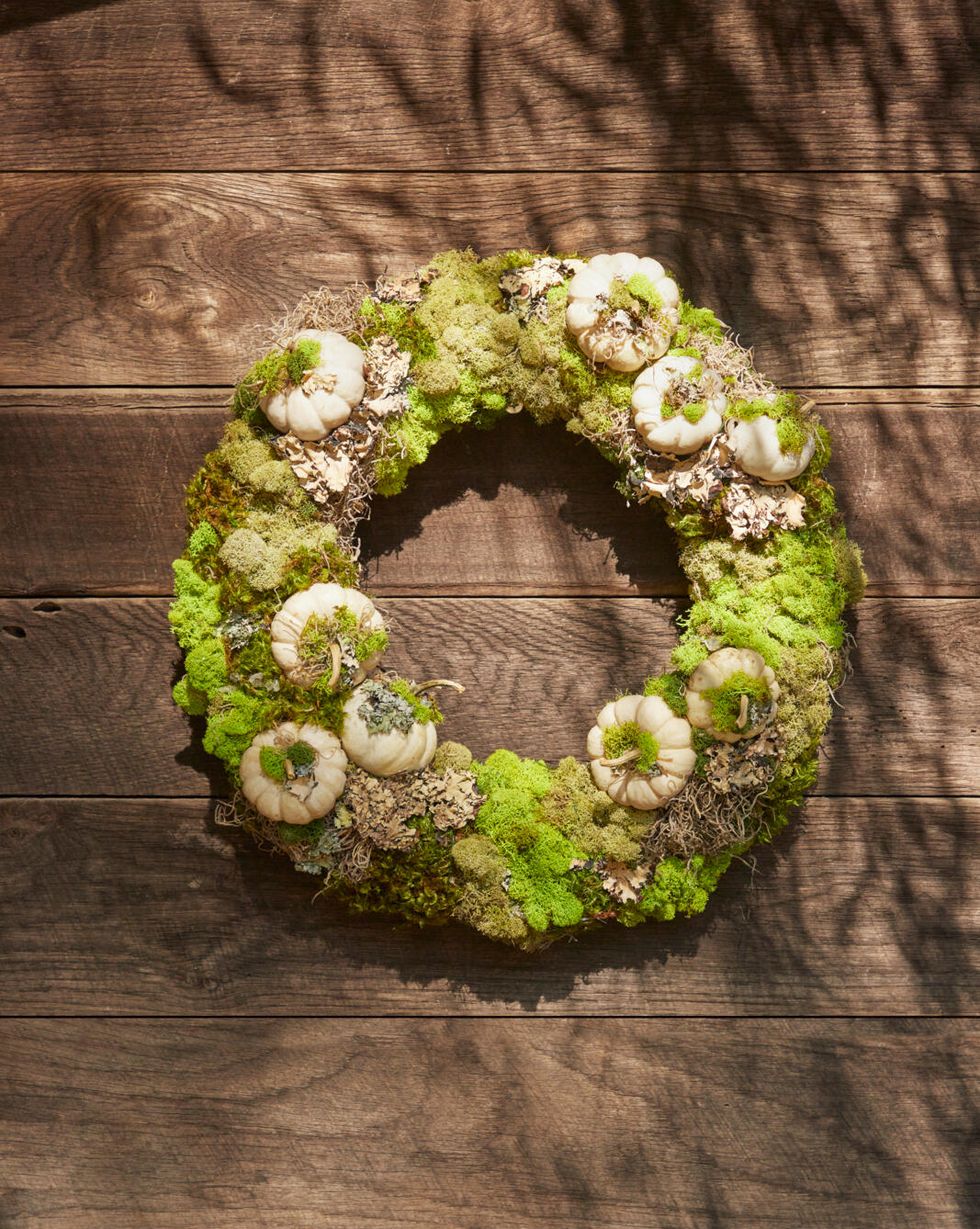 fall wreath made from dried moss, lichen and mini white pumpkins hung on a brown barn wall
