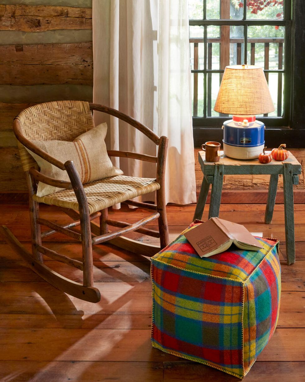 foot pouf made from plaid fabric set in a cabin in front of a rocking chair and window