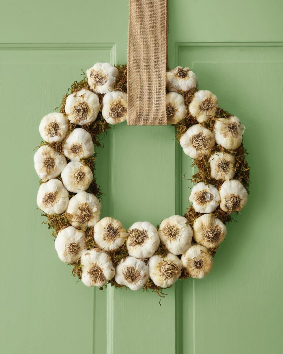 halloween wreath made from whole garlic cloves and moss on a light green door