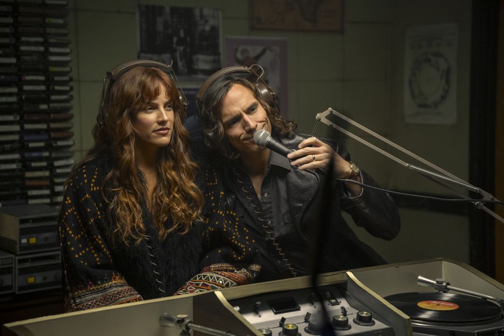 riley keough and sam claflin in character for ﻿daisy jones and the six﻿ sit in front of a microphone with headphones on