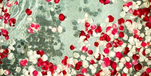 red and white rose petals floating in clear water bath with flower petals and salt romantic mood