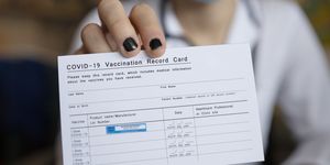 doctor holding covid 19 vaccination record card