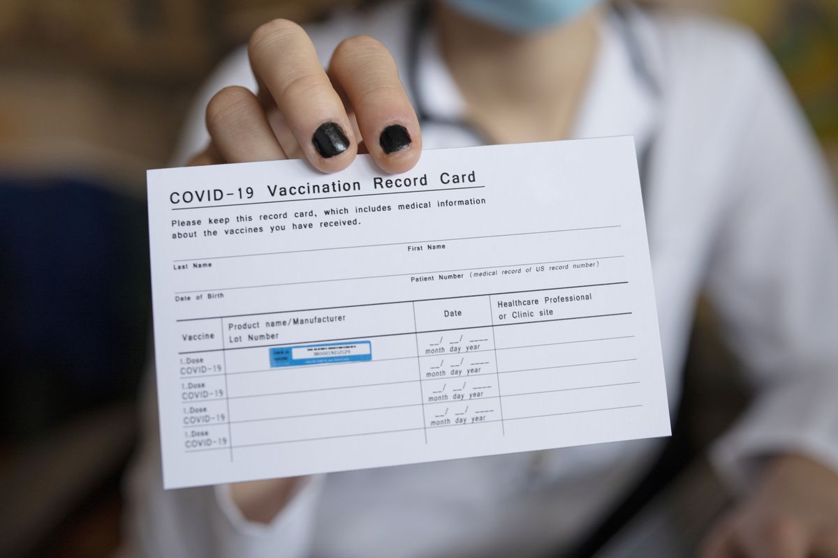 doctor holding covid 19 vaccination record card