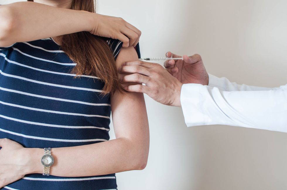 a doctor is giving a vaccine to a young woman
