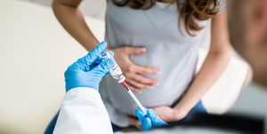 doctor preparing vaccine injection for pregnant woman at clinic