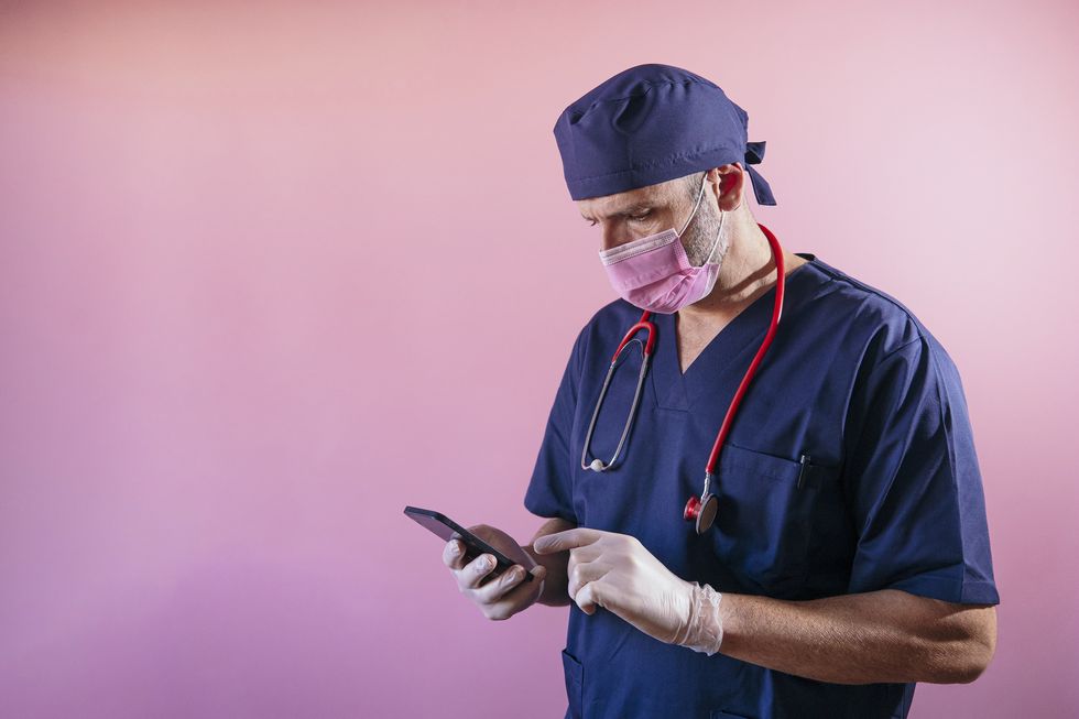 doctor using a smart phone with pink background