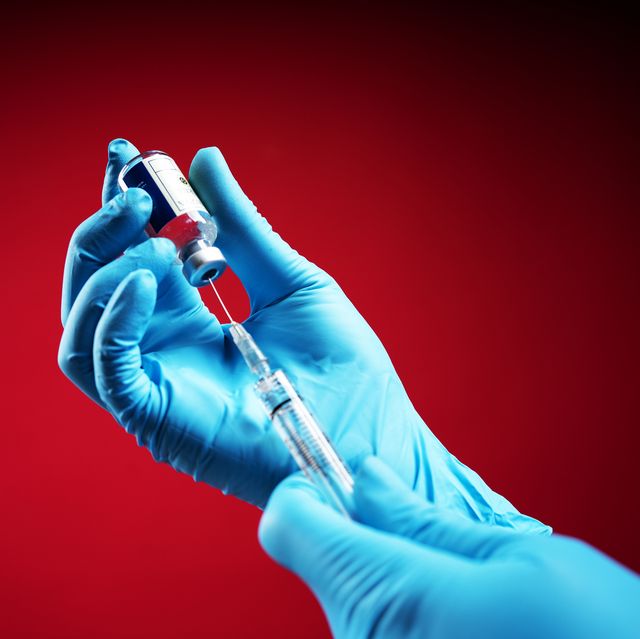 doctor wearing surgical gloves and preparing the coronavirus covid 19 vaccine 2019 ncov first coronavirus vaccine found in the world with red background isolated