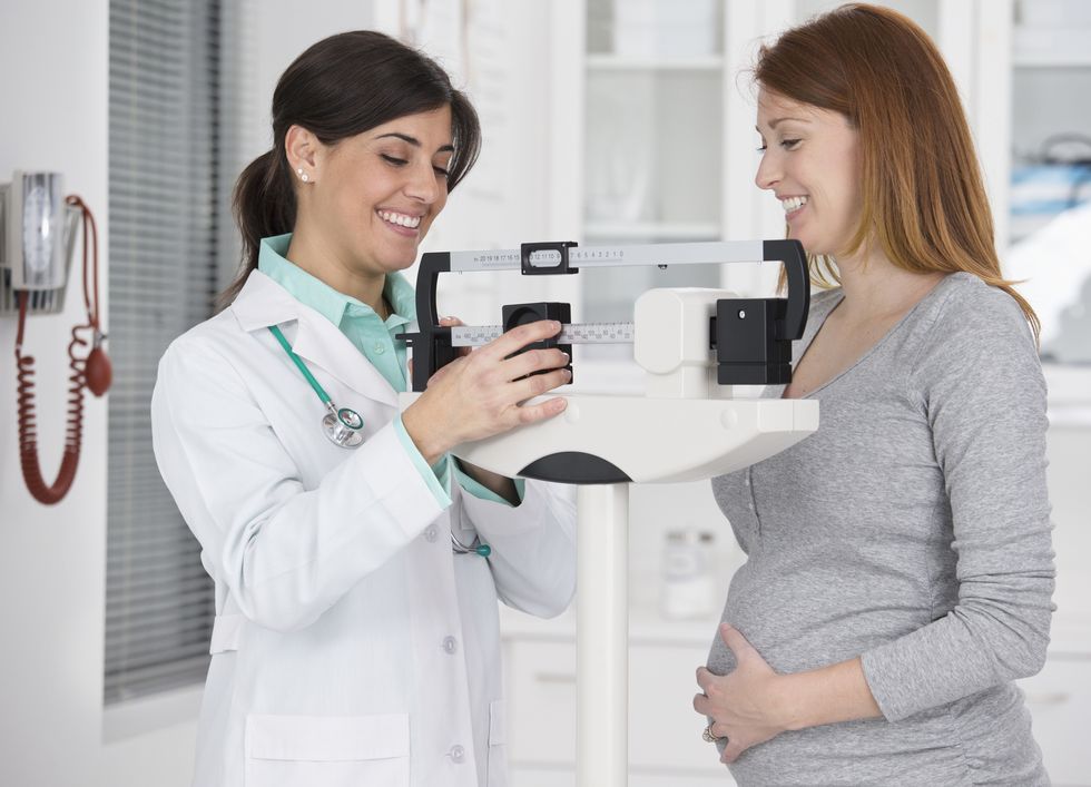 doctor weighing pregnant woman in office