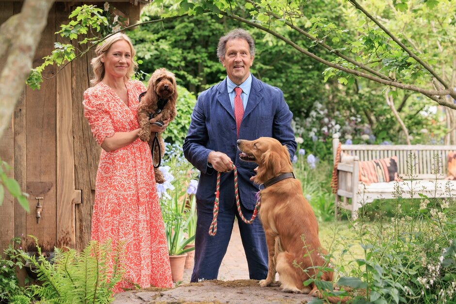 a couple standing together in a garden with two dogs