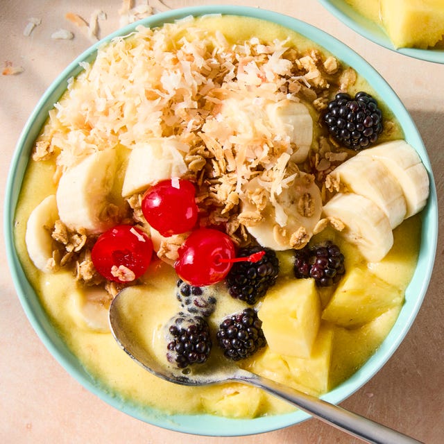 Dole Whip Smoothie Bowl pineapple dole whip smoothie bowl in a blue bowl topped with pineapple, banana, blackberries, cherries, and toasted coconut flakes