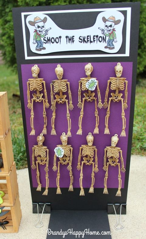 8 small plastic skeletons hung on board for shoot the skeleton, a halloween party game for kids