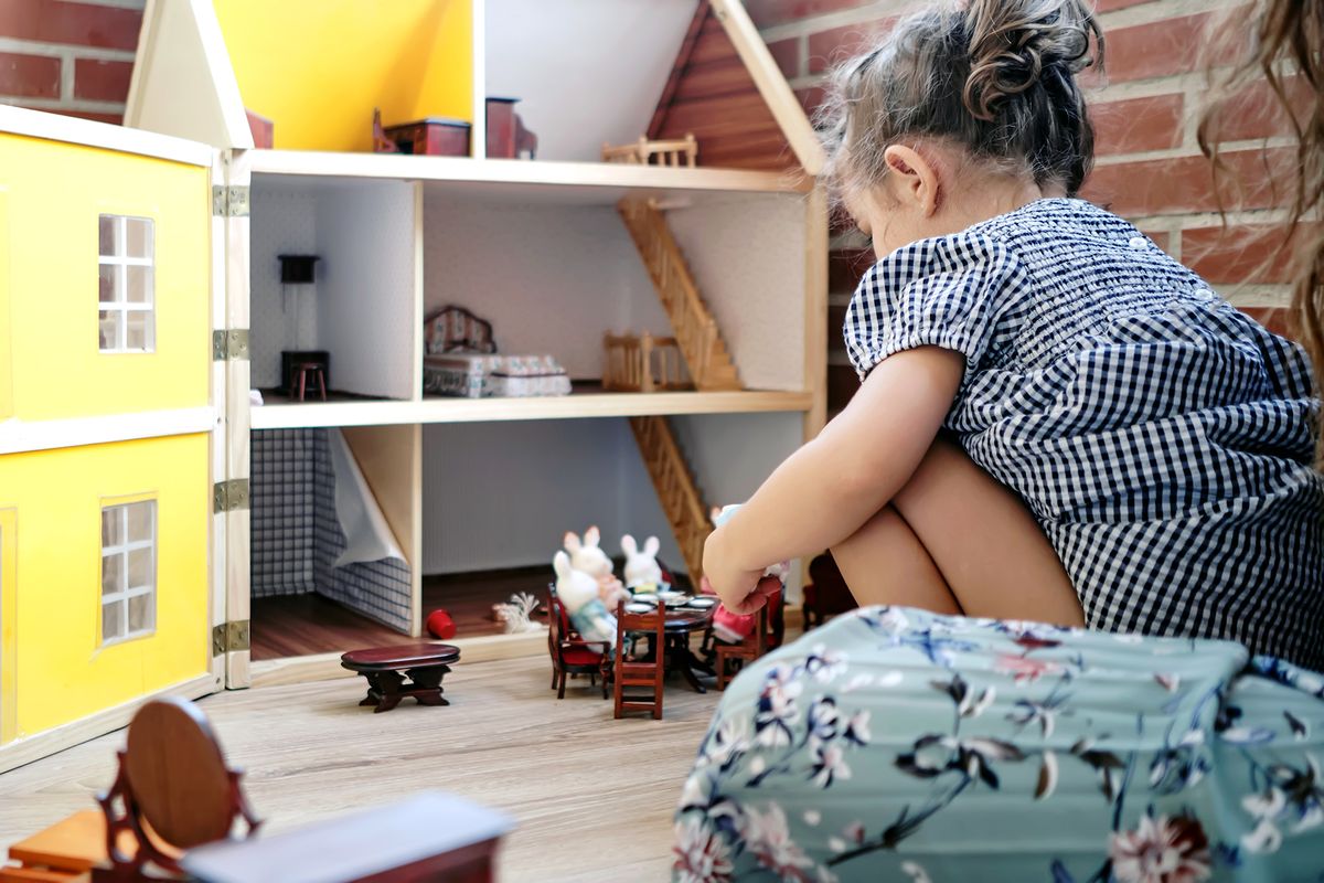 young kid playing with doll house