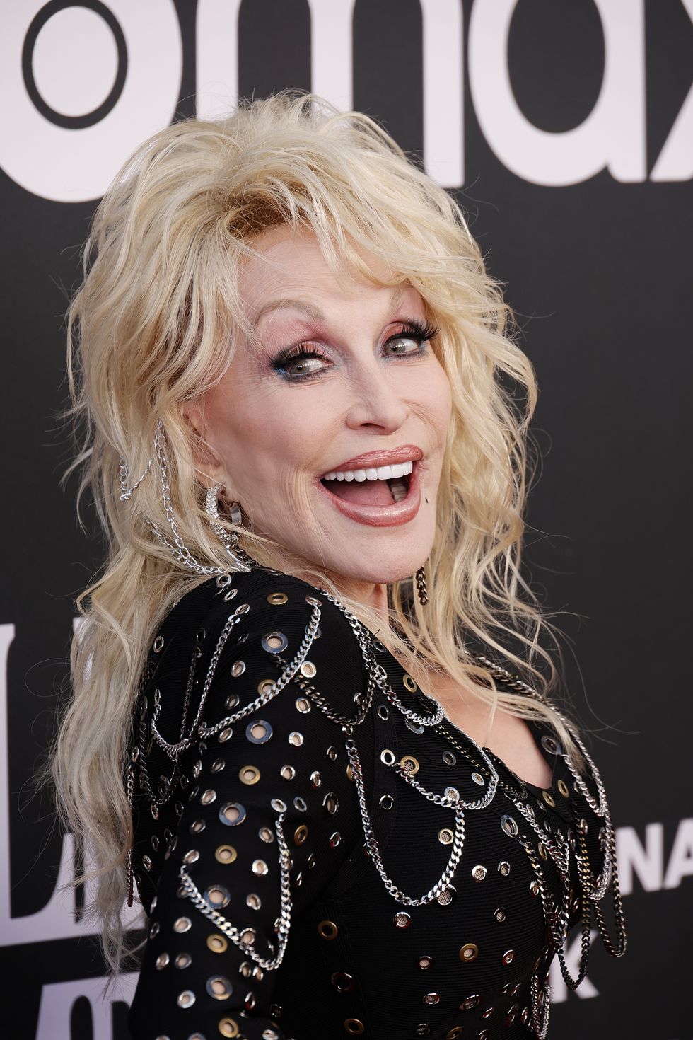 dolly parton looking to her right and toward a camera and smiling for a picture