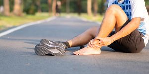 un corredor sentado en la carretera y con el pie descalzo se duele del empeine o parte superior del pie