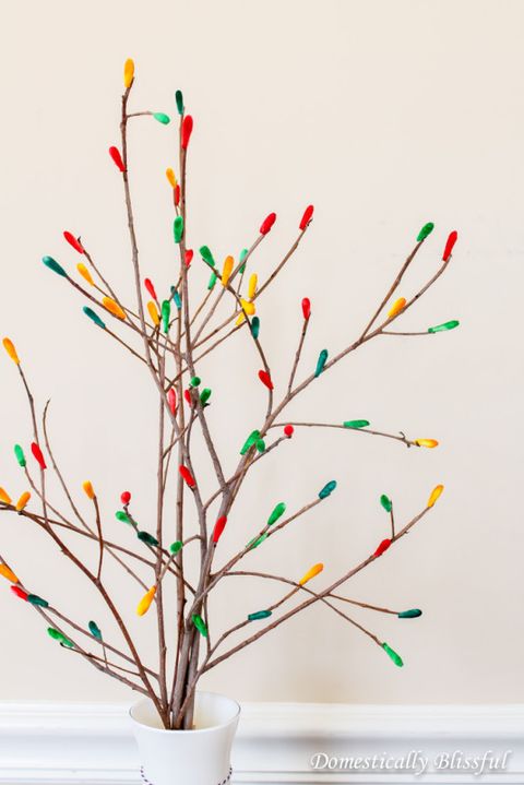 bare branches with colored qtips on the end in a white vase