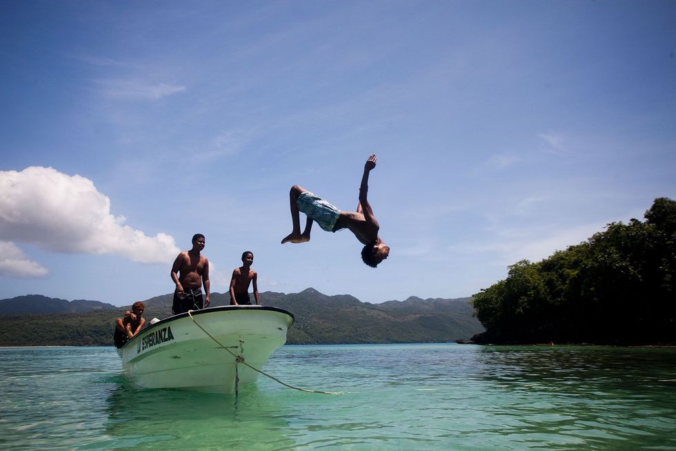 Een lokale jongen doet een backflips van een boot in de zee bij de Saman Peninsula