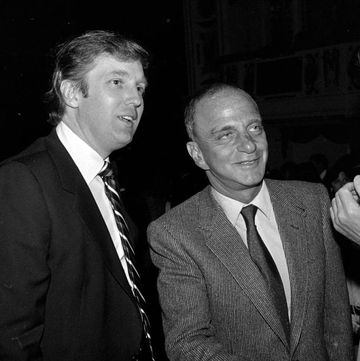 roy cohn shaking a hand as donald trump stands to his right smiling
