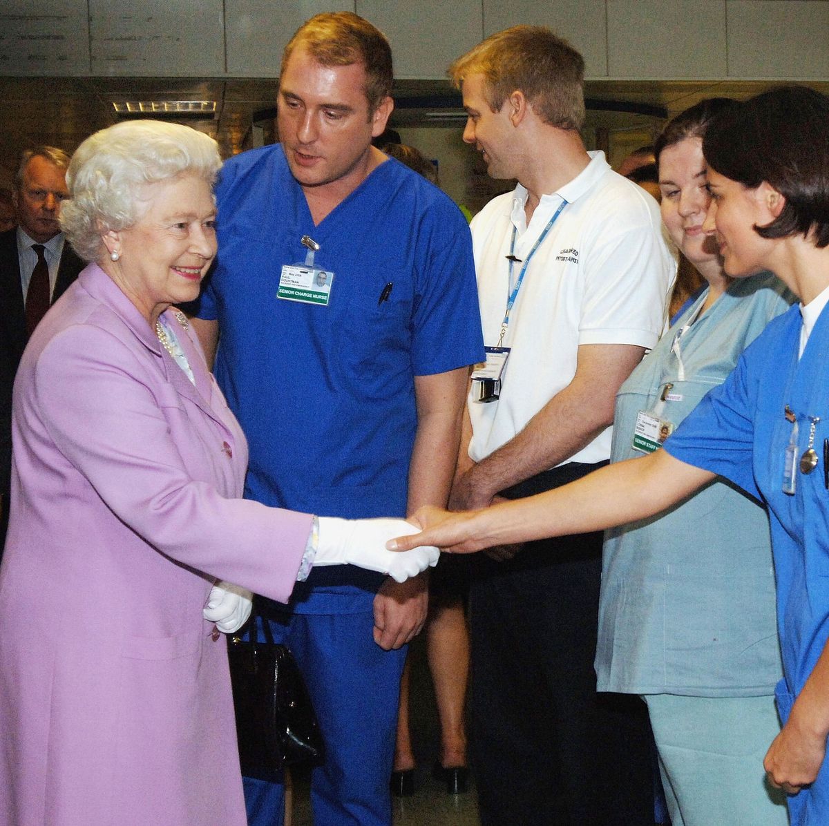 london, england   july 8  no uk sales for 28 days hm queen elizabeth ii, the queen, is introduced to accident and emergency staff a  e by senior charge nurse paul courtman during her visit to the royal london hospital to meet staff and victims of the terrorist bomb explosions on june 8, 2005 in london, england  photo by pooltim graham picture librarygetty images