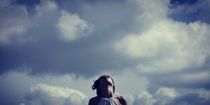 Low Angle View Of Mid Adult Woman Standing Against Cloudy Sky