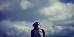 Low Angle View Of Mid Adult Woman Standing Against Cloudy Sky