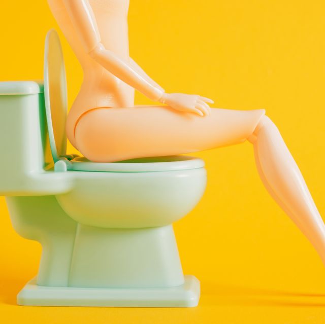 dool sits on green toy toilet bowl on yellow background
