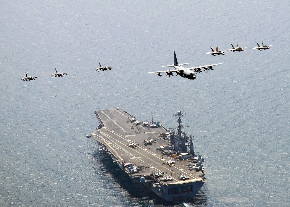 a group of airplanes flying over a ship in the water