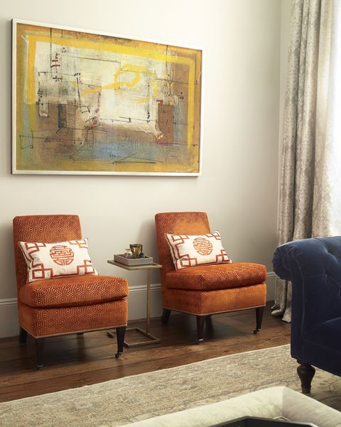 abstract painting above two orange chairs
