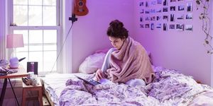 woman wrapped in blanket using laptop in dorm room
