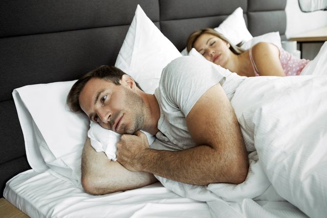 woman in bed can not sleep because her husband is snoring
