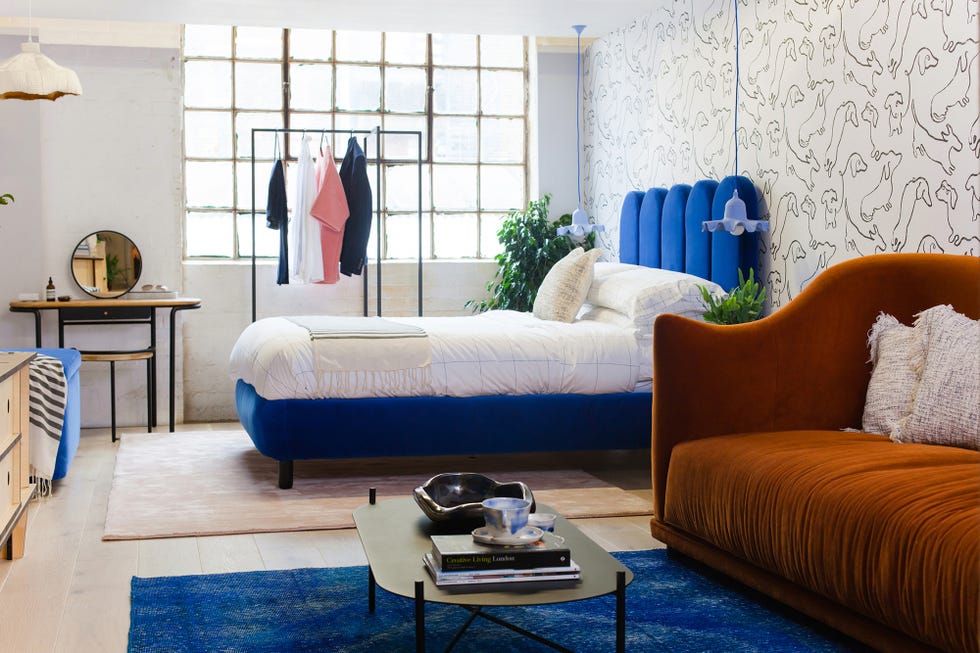 dormitorio con cama de terciopelo azul y zona de estar