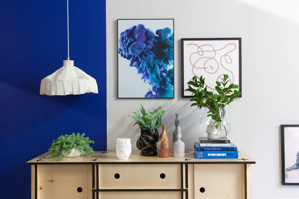 cómoda de madera decorada con plantas y pared pintada en blanco y azul