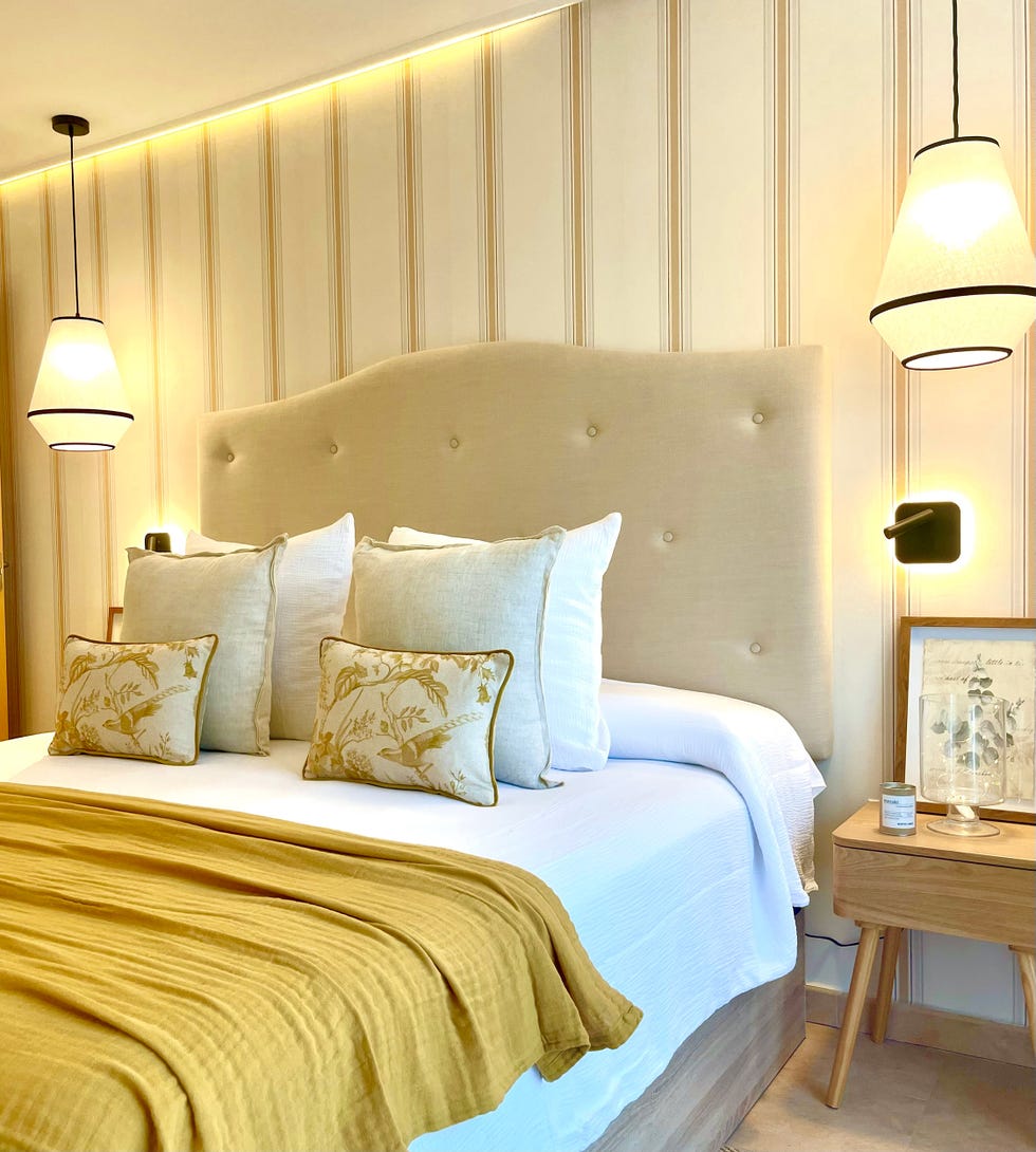 dormitorio con papel pintado a rayas y cabecero tapizado en beige