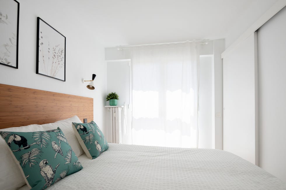 dormitorio decorado en tonos blancos con acentos verdes y un cabecero de madera