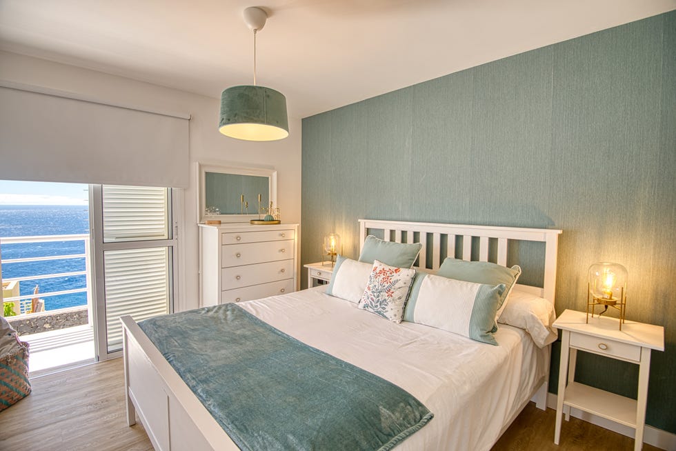 dormitorio con cama blanca y papel pintado azul