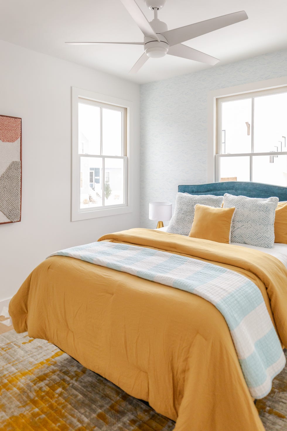 cama con cabecero azul de terciopelo y funda nórdica amarilla