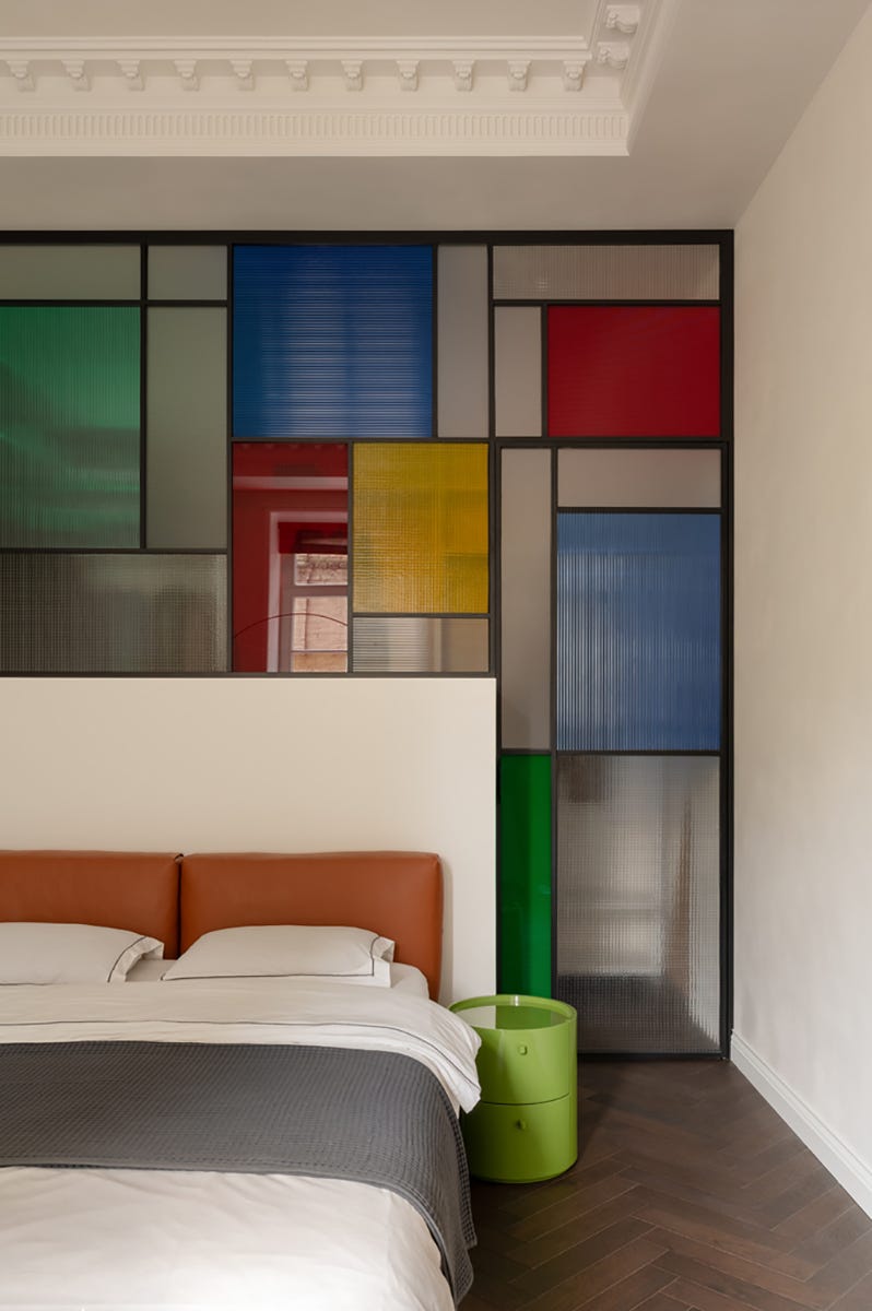 dormitorio con cabecero de piel y cristalera detras, estilo mondrian